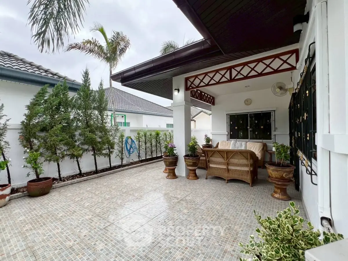 Charming patio with cozy seating in a suburban home, surrounded by lush greenery.