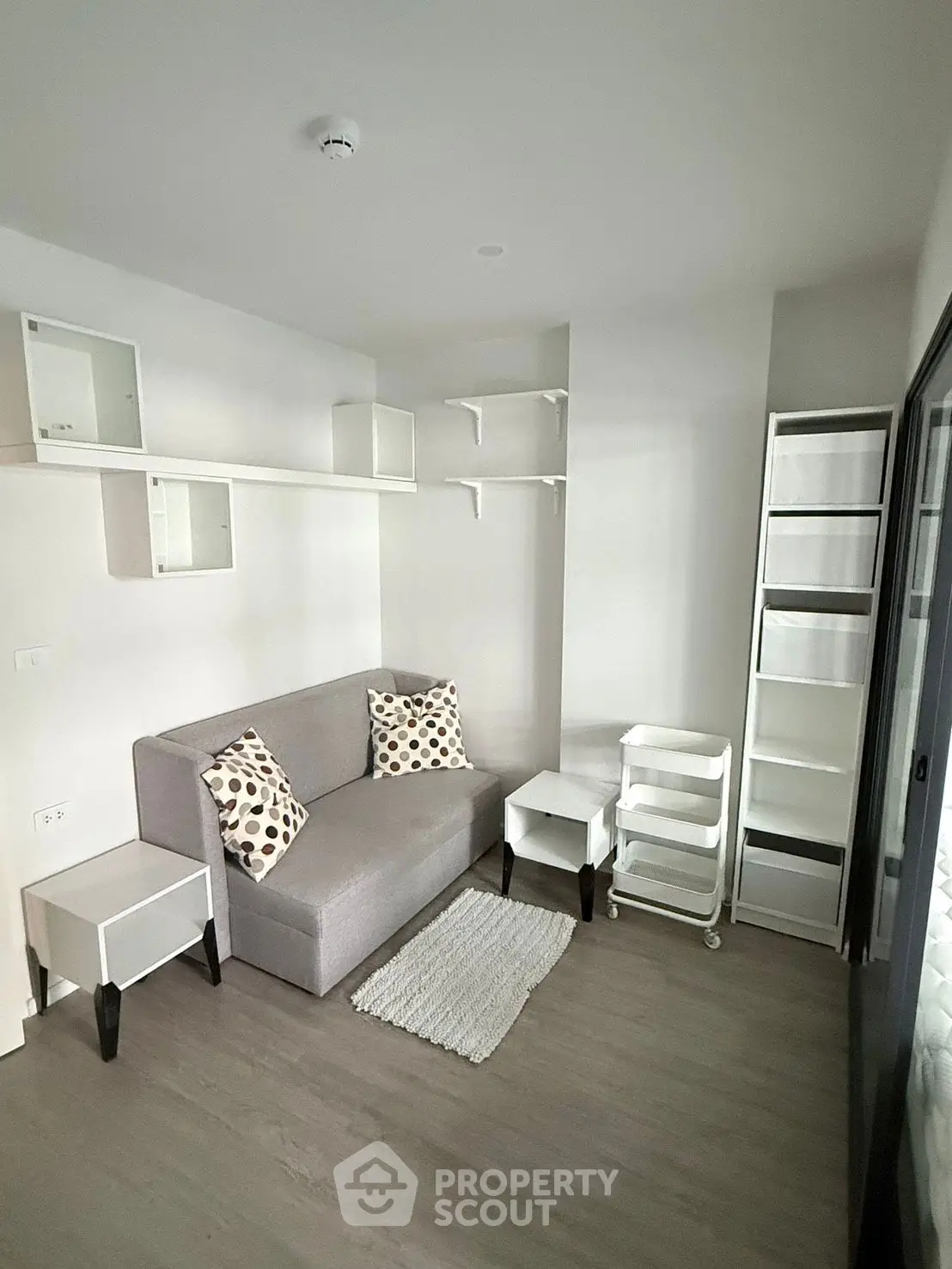 Modern minimalist living room with sleek white shelves and cozy gray sofa