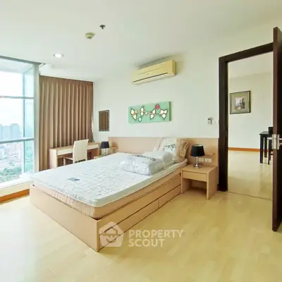 Spacious bedroom with city view, modern furnishings, and natural light in a high-rise apartment.