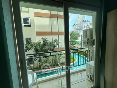 Charming balcony view overlooking lush greenery and pool in modern apartment complex.