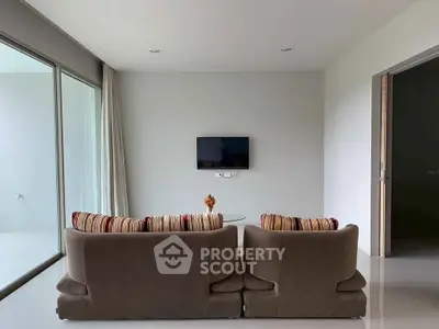 Modern living room with sleek design, featuring a wall-mounted TV and cozy seating area.