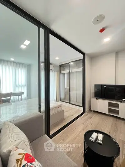 Modern living room with glass partition, stylish decor, and natural light in a contemporary apartment.