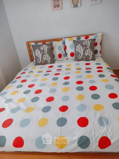 Cozy bedroom with colorful polka dot bedding and decorative pillows, perfect for a vibrant home.