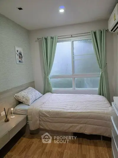 Cozy bedroom with single bed, soft lighting, and large window with green curtains.