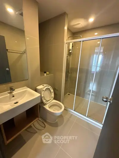 Modern bathroom with glass shower and sleek fixtures in contemporary apartment.