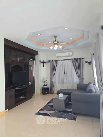Spacious living room with modern decor and ceiling fan, featuring a cozy gray sofa and entertainment center.
