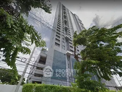 Modern high-rise building with lush greenery and clear sky view, ideal for urban living.