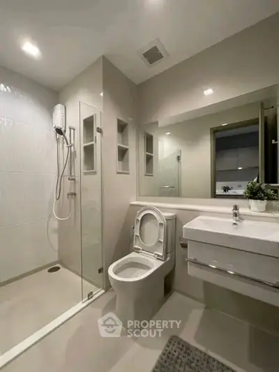 Modern bathroom with sleek fixtures and glass shower enclosure.
