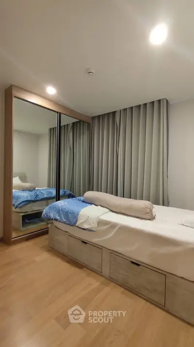 Modern bedroom with mirrored wardrobe and wooden flooring