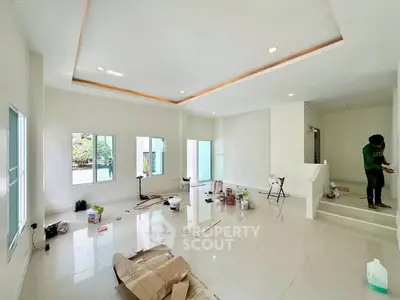 Spacious modern living room under renovation with large windows and glossy tiled floors.