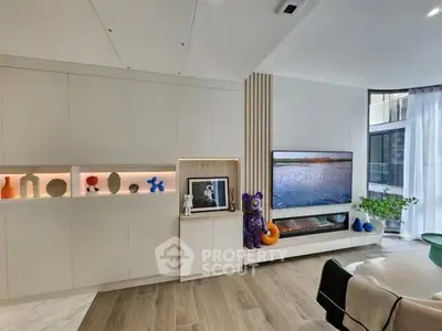 Modern living room with sleek built-in cabinetry and large TV, featuring elegant decor and natural light.