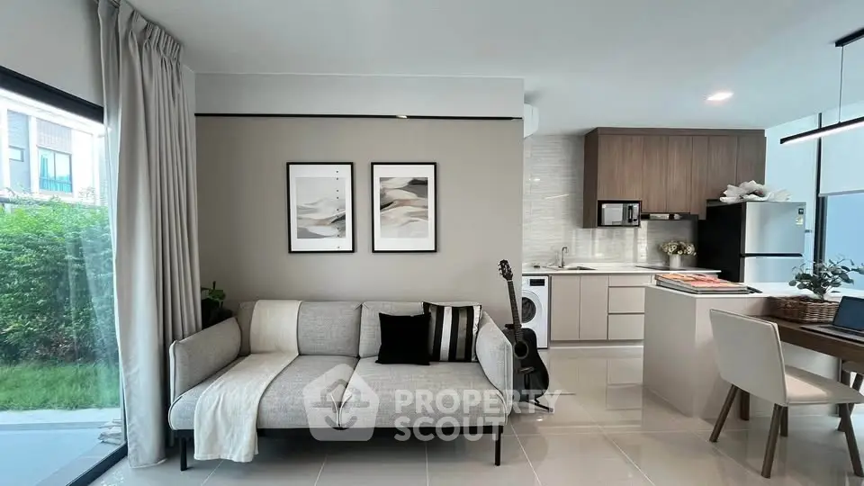Modern open-layout living room and kitchen with stylish decor and natural light.