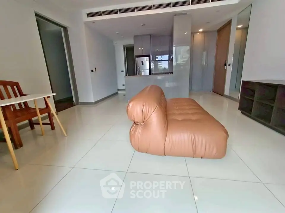 Spacious modern living room with sleek furniture and open kitchen layout.