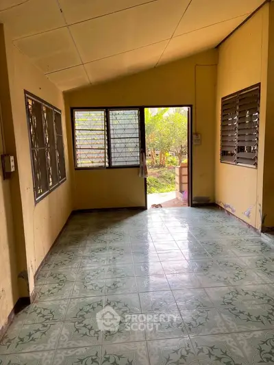 Spacious room with tiled floor and large windows offering garden view