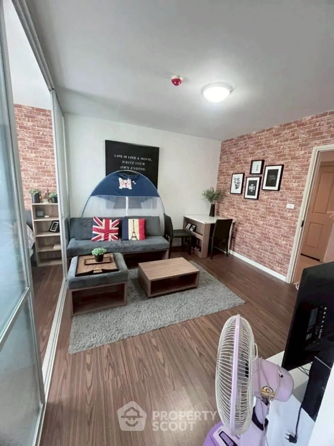 Charming living room with modern decor and cozy seating area, featuring stylish brick accent wall.