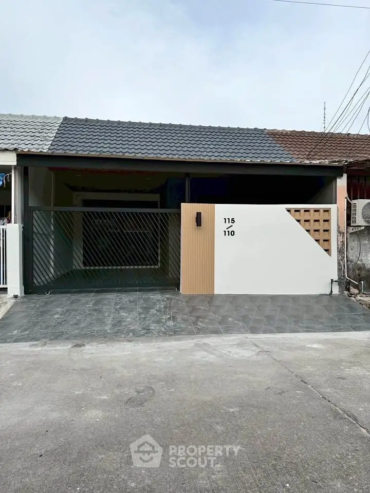Modern single-story house with sleek exterior design and gated driveway.