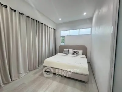 Modern bedroom with elegant curtains and stylish bed in a bright, airy space.