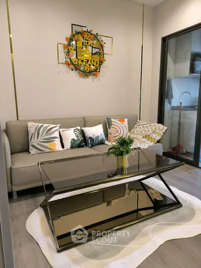 Stylish living room with modern glass coffee table and cozy sofa adorned with decorative pillows.
