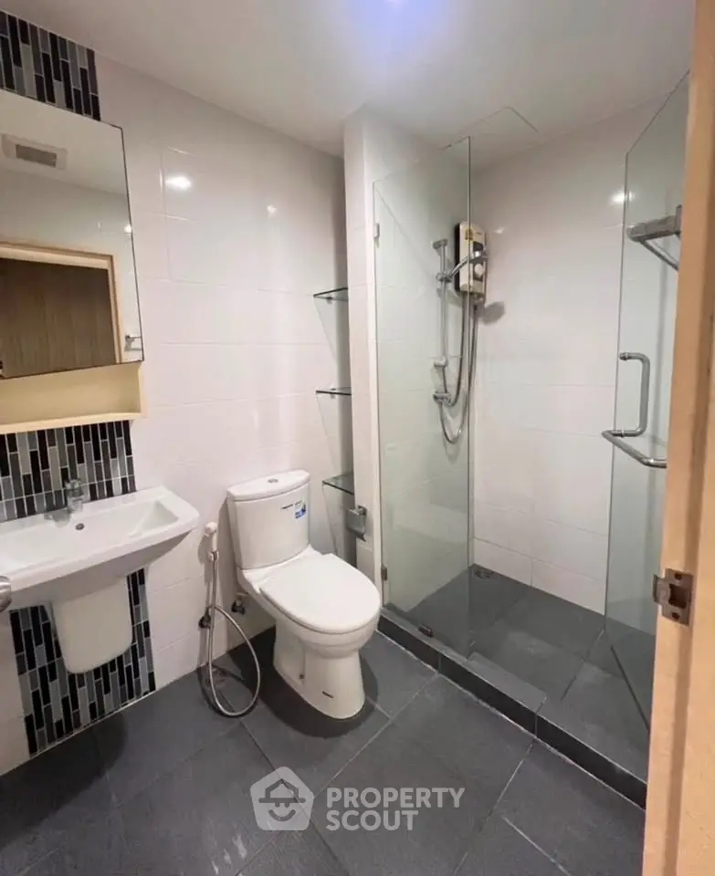 Modern bathroom with glass shower and sleek fixtures in contemporary apartment.
