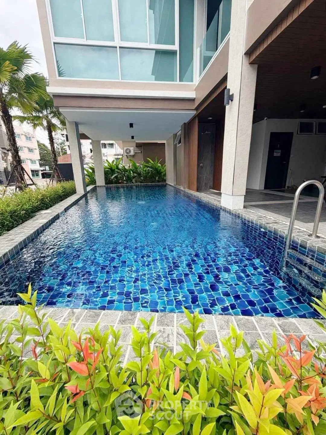 Luxurious modern apartment with stunning poolside view and lush greenery.