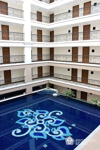 Luxurious multi-level residential building with an ornate pool centerpiece, surrounded by elegant balconies and lush greenery.