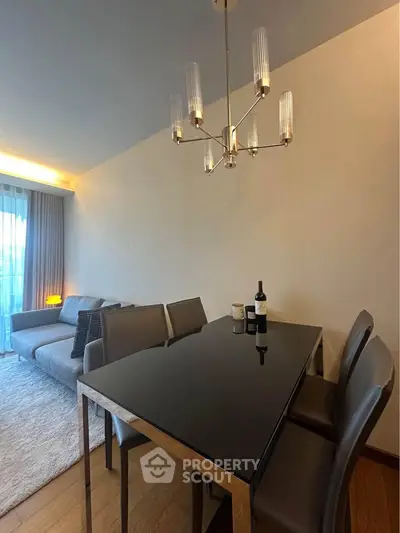Modern dining area with sleek table and elegant chandelier in a stylish living room setting.