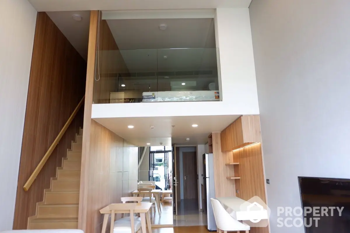 Modern duplex apartment with elegant wooden staircase leading to an upper level, showcasing a sleek design with an open-plan living area and abundant natural light.