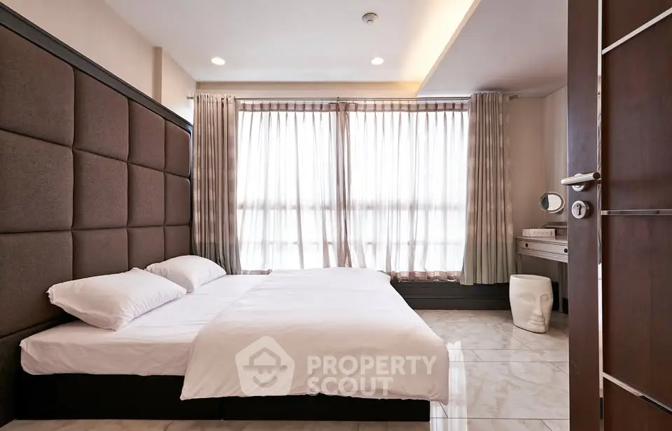 Modern bedroom with elegant decor and large windows for natural light.