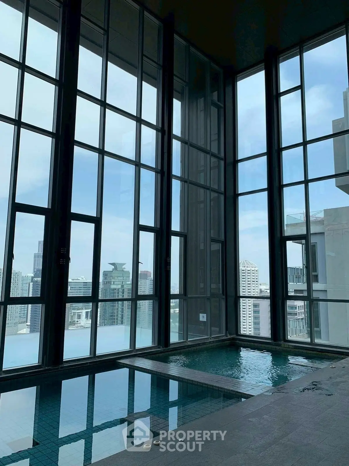 Luxurious indoor pool with stunning city views through floor-to-ceiling windows.