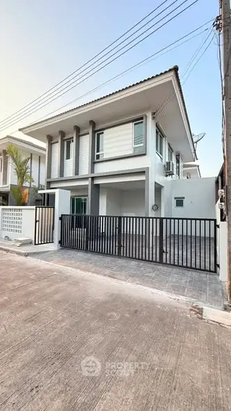 Modern two-story house with sleek design and gated entrance in a suburban neighborhood.