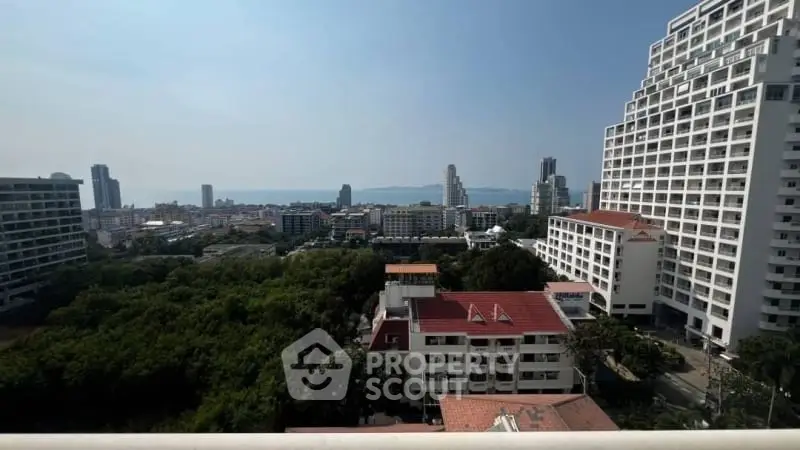 Stunning cityscape view from high-rise balcony with ocean in the distance, ideal for urban living.