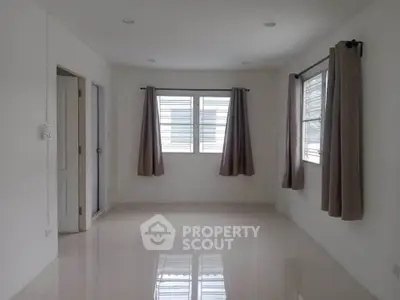 Spacious empty room with large windows and curtains, perfect for customization.