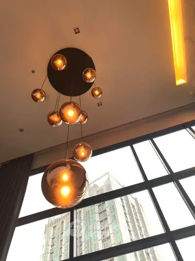 Modern high-rise apartment with stylish pendant lighting and large windows offering city views.