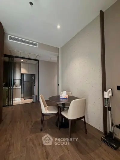 Modern dining area with elegant table and chairs, adjacent to a sleek kitchen with stainless steel appliances.