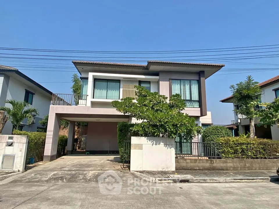 Modern two-story house with driveway and lush greenery in a suburban neighborhood.