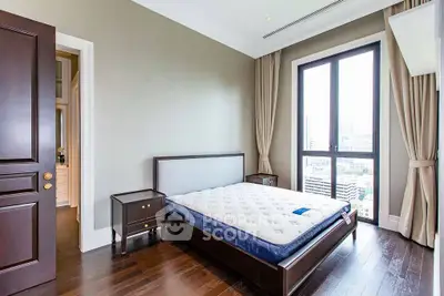 Spacious bedroom with large window offering city views, featuring elegant wooden flooring and modern furnishings.
