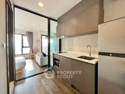 Modern open-layout kitchen with sleek cabinetry and adjacent living area in a stylish apartment.
