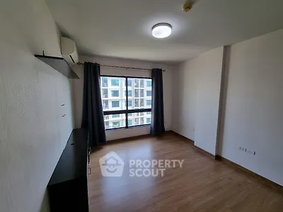 Spacious empty room with large window and wooden flooring in modern apartment.