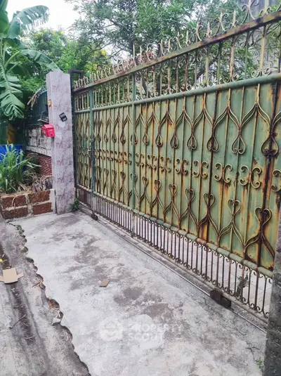 Charming rustic gate with intricate ironwork in a lush garden setting, perfect for a cozy home entrance.