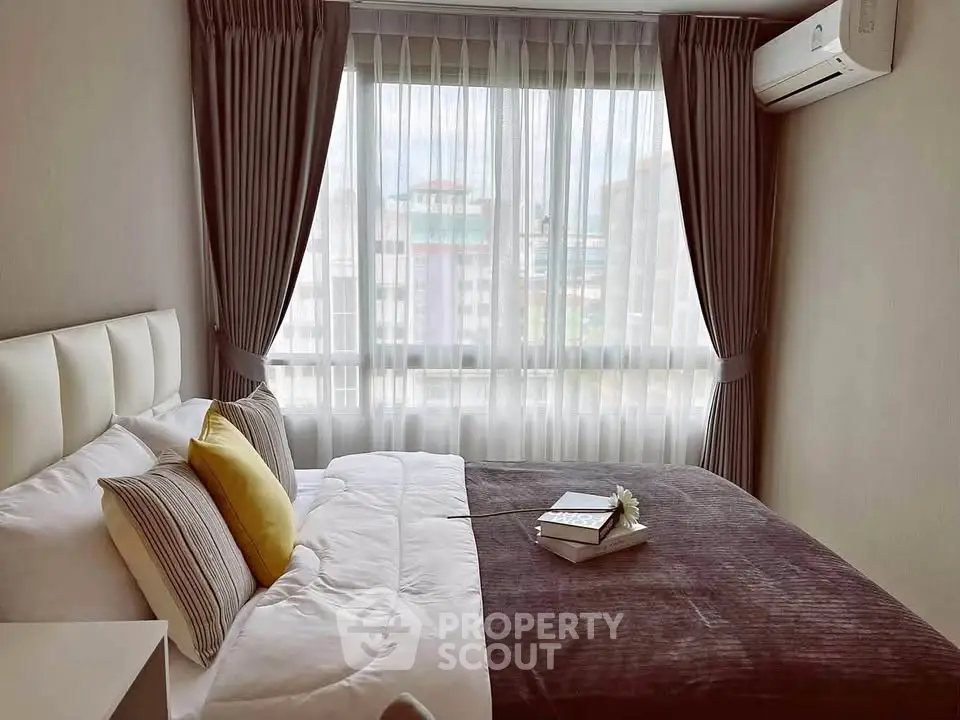 Cozy bedroom with plush bedding and large window offering natural light.