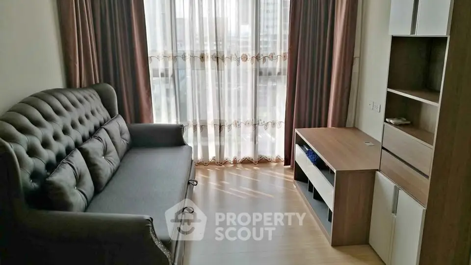 Cozy living room with elegant sofa and natural light through large window.
