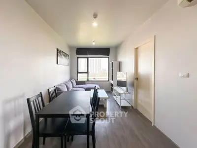 Modern living room with sleek furniture and large window offering city views.