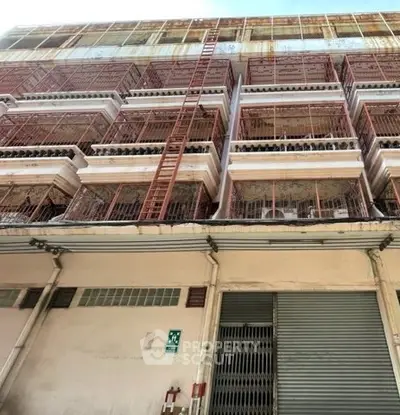 Urban building exterior with multiple balconies and safety ladder, showcasing city architecture.