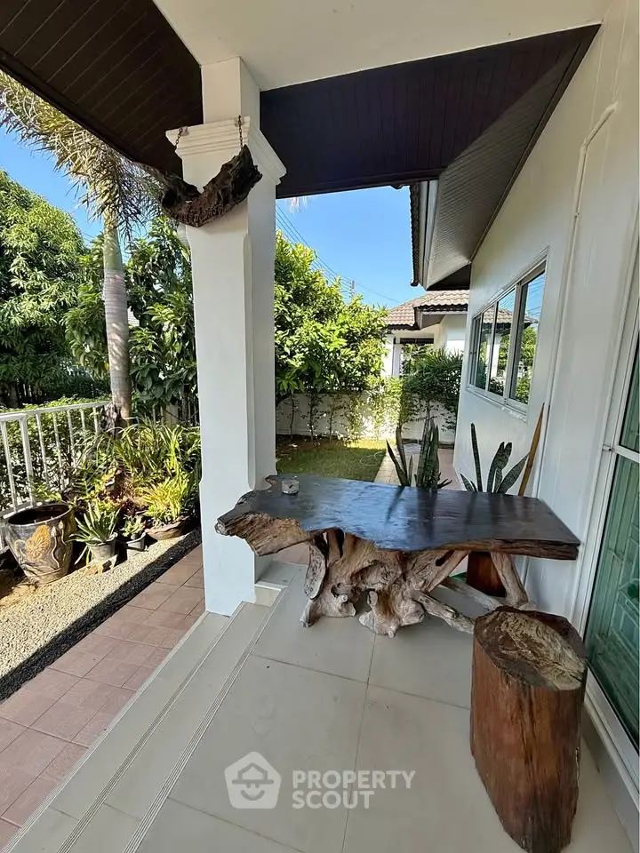 Charming outdoor patio with rustic wooden table and lush garden view, perfect for relaxation and entertaining.