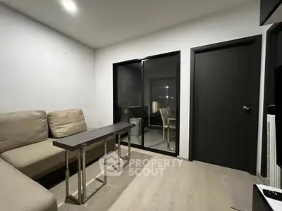 Modern living room with sleek furniture and glass door leading to dining area.