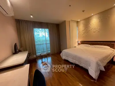 Spacious bedroom with elegant decor and large window offering natural light.