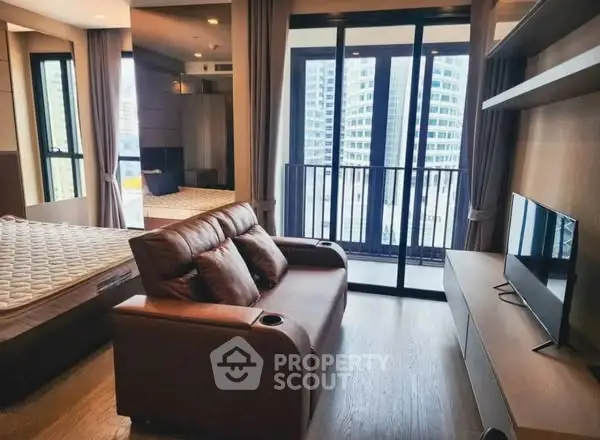 Modern studio apartment with balcony and city view, featuring cozy living area and sleek furnishings.