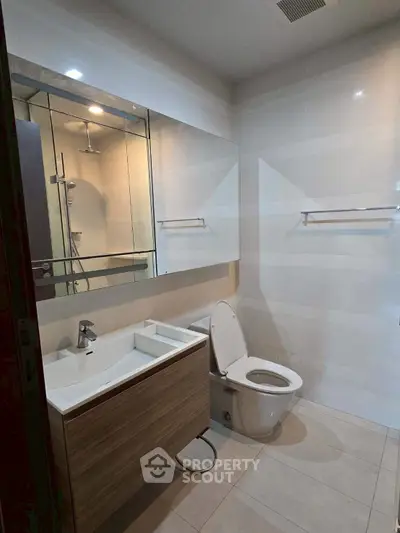 Modern bathroom with sleek fixtures and large mirror in a contemporary home.