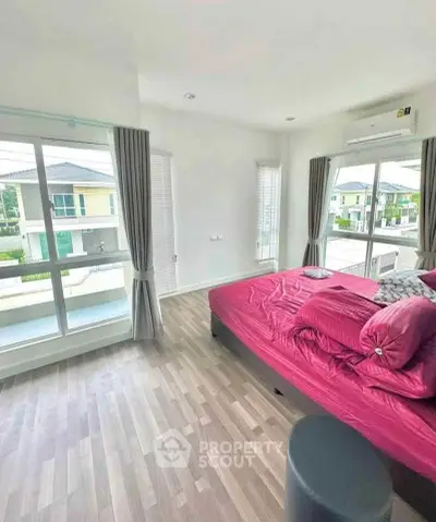 Spacious bedroom with large windows and modern decor in a bright home.
