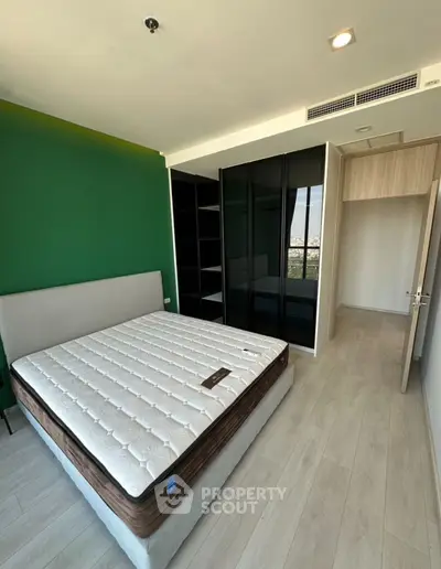 Modern bedroom with green accent wall and large wardrobe